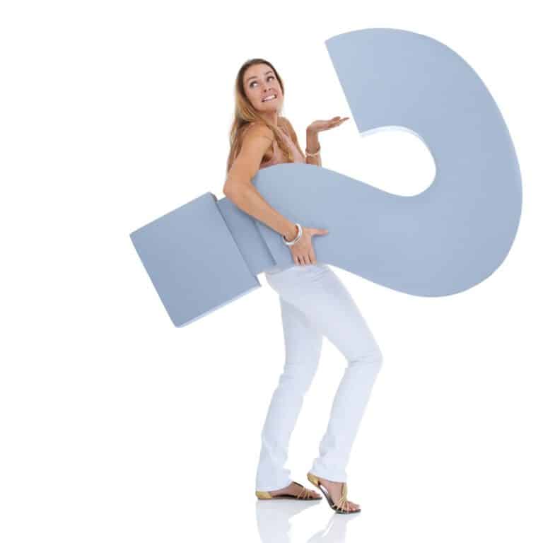 Foto von einer europäischen Frau mit einem übergroßem Fragezeichen unter ihrem Arm.